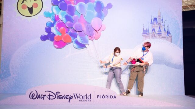 Karol Pinheiro e Maqui Nóbrega seguram os balões da Disney com o Castelo da Cinderela ao fundo
