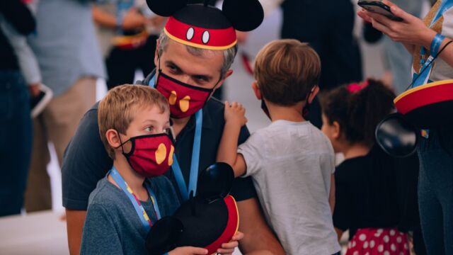 Pai e filho curtem o evento com chapéu e máscara do Mickey